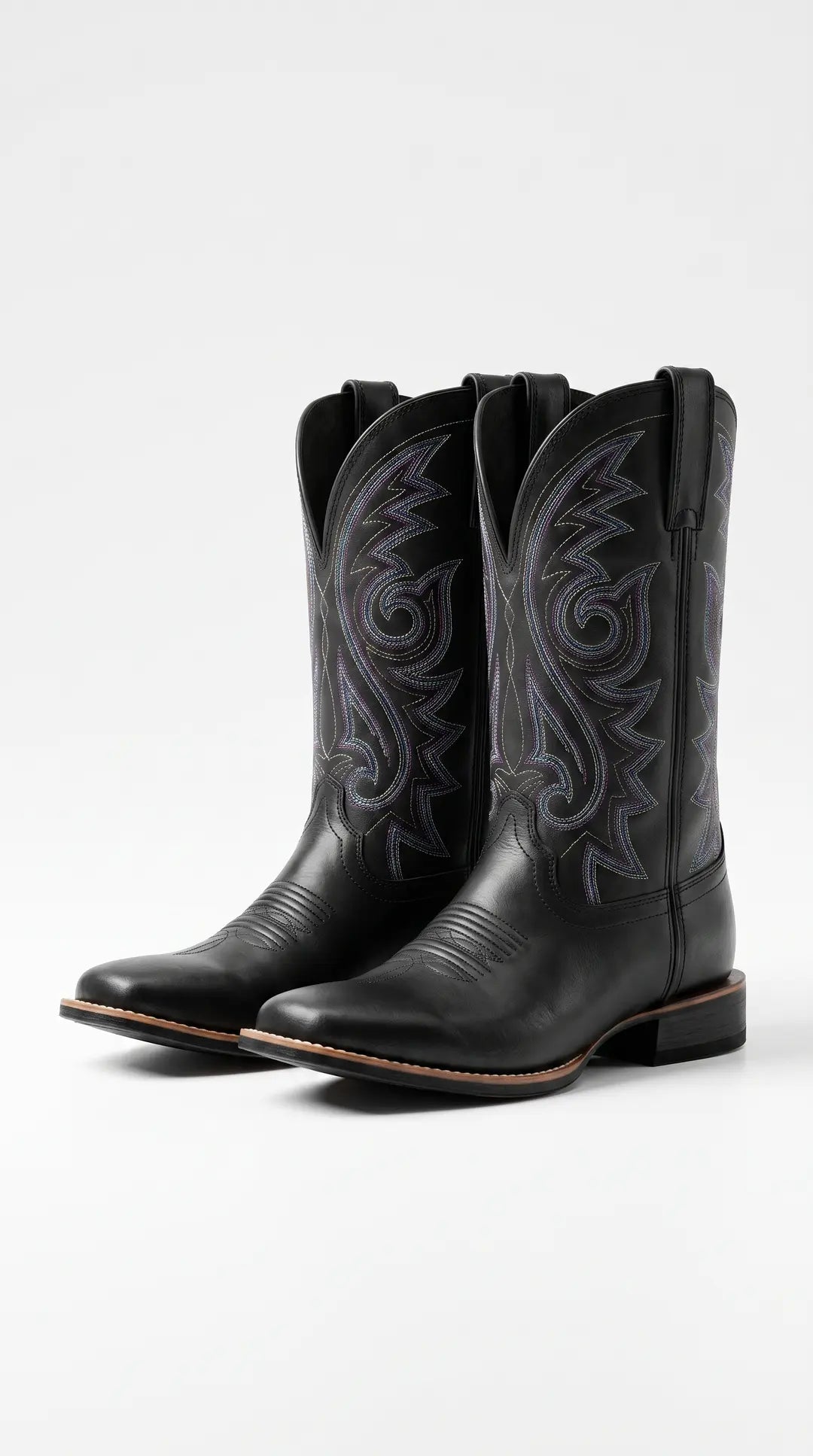 Par de botas vaqueras negras de punta cuadrada y tacón, con bordados decorativos en hilos de colores en la caña.