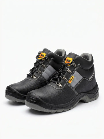 Un par de botas de seguridad negras con suelas grises, cordones negros, ojales metálicos y detalles de costura blanca y franjas grises laterales. Cada bota tiene una etiqueta amarilla y roja cerca de los cordones.