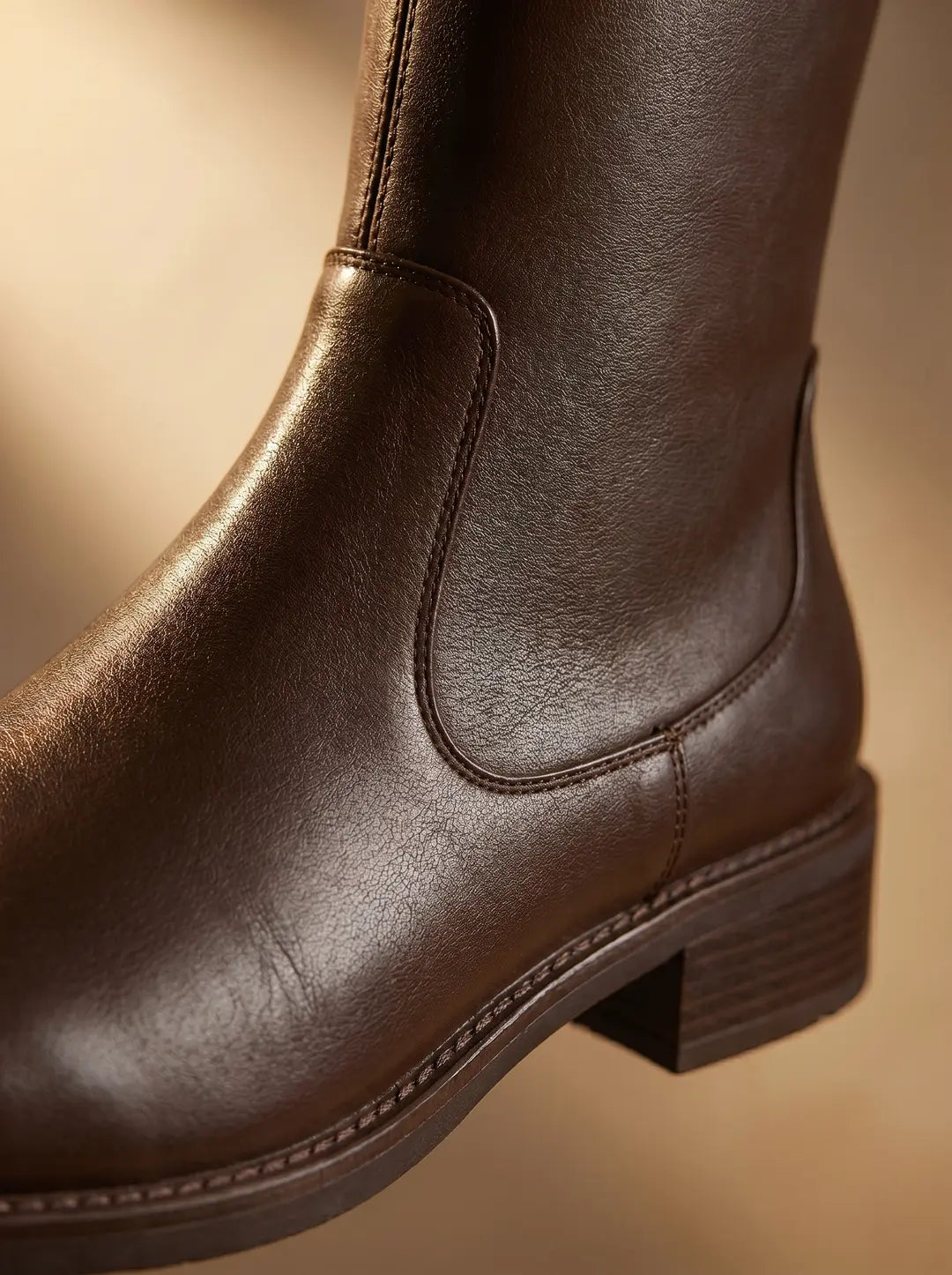 Bota de cuero marrón con costuras visibles y tacón de bloque.