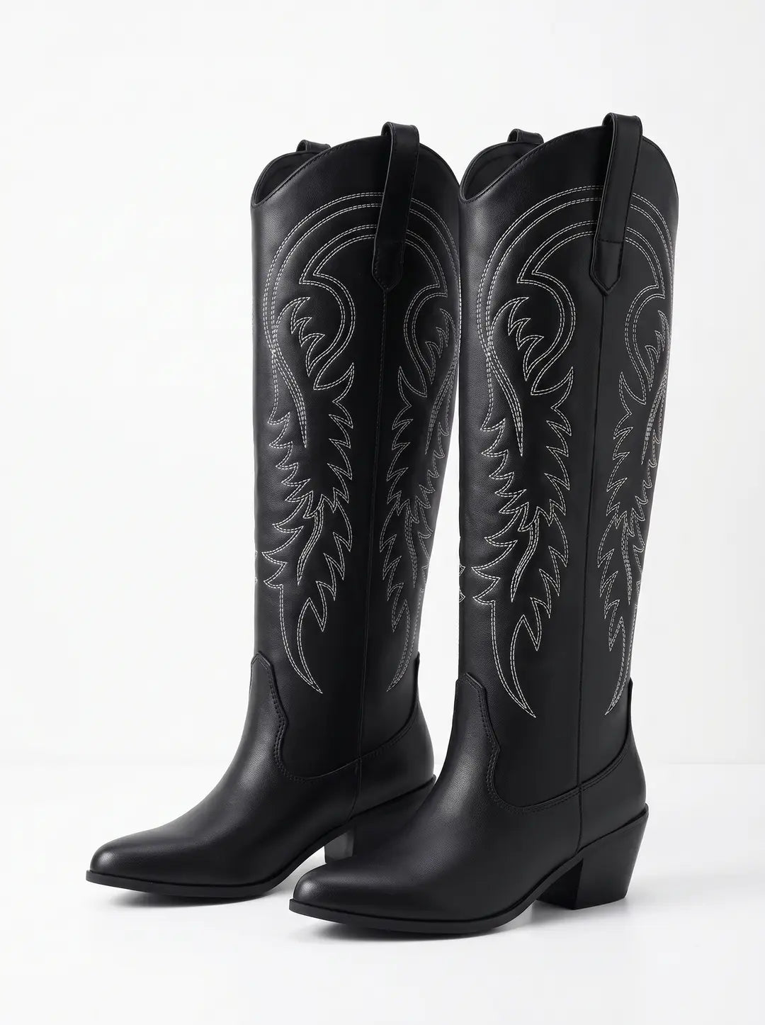 Dos botas negras de estilo vaquero con caña alta, costuras decorativas blancas y tacón.