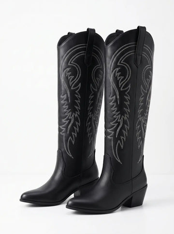 Dos botas negras de estilo vaquero con caña alta, costuras decorativas blancas y tacón.