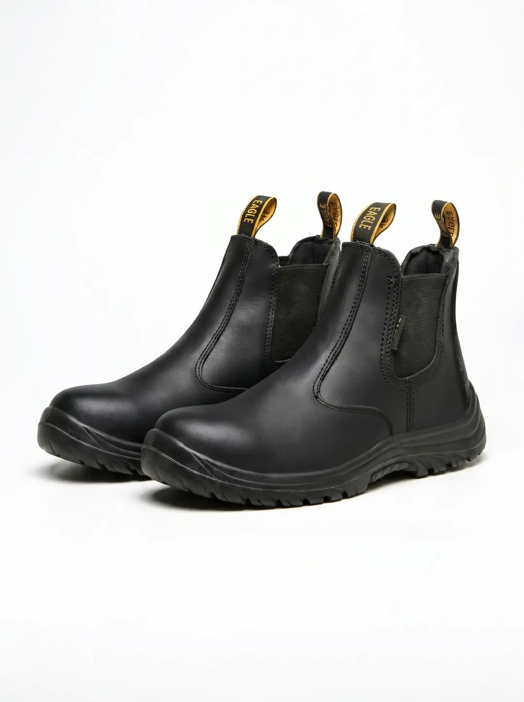 Par de botas de trabajo negras tipo Chelsea. Presentan paneles elásticos laterales, puntera protectora y suelas robustas. Las lengüetas traseras son negras con texto amarillo 'EAGLE'.