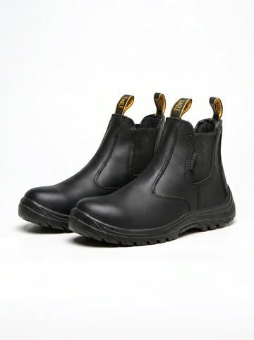 Par de botas de trabajo negras tipo Chelsea. Presentan paneles elásticos laterales, puntera protectora y suelas robustas. Las lengüetas traseras son negras con texto amarillo 'EAGLE'.