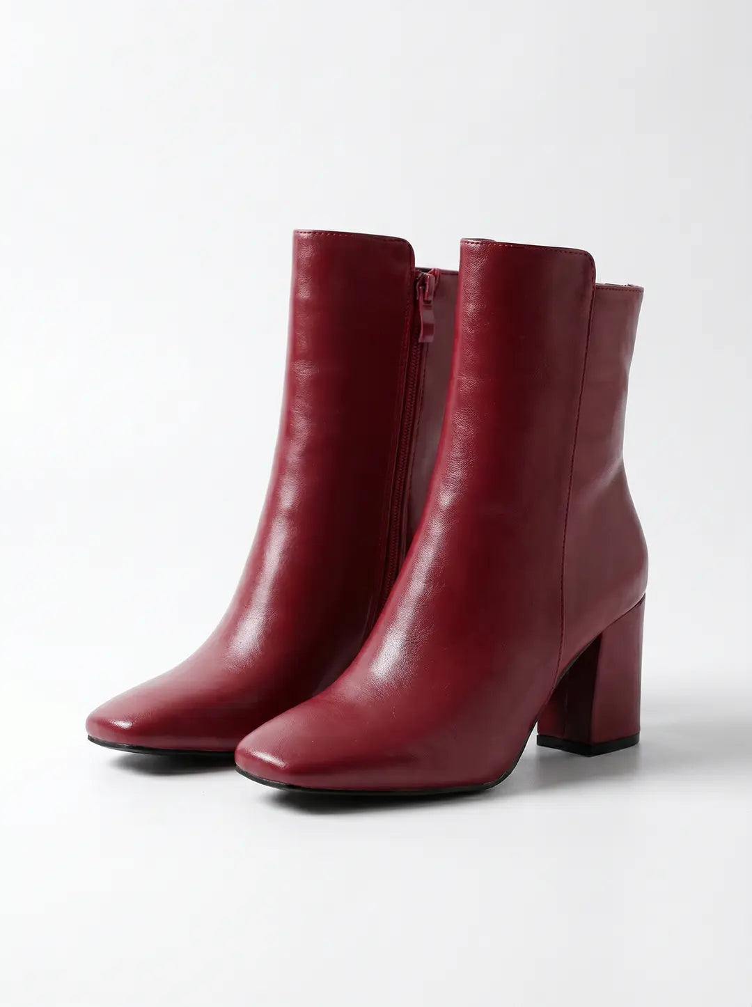Un par de botines de mujer de color rojo oscuro con puntera cuadrada, tacón de bloque y cremallera lateral, sobre un fondo blanco.