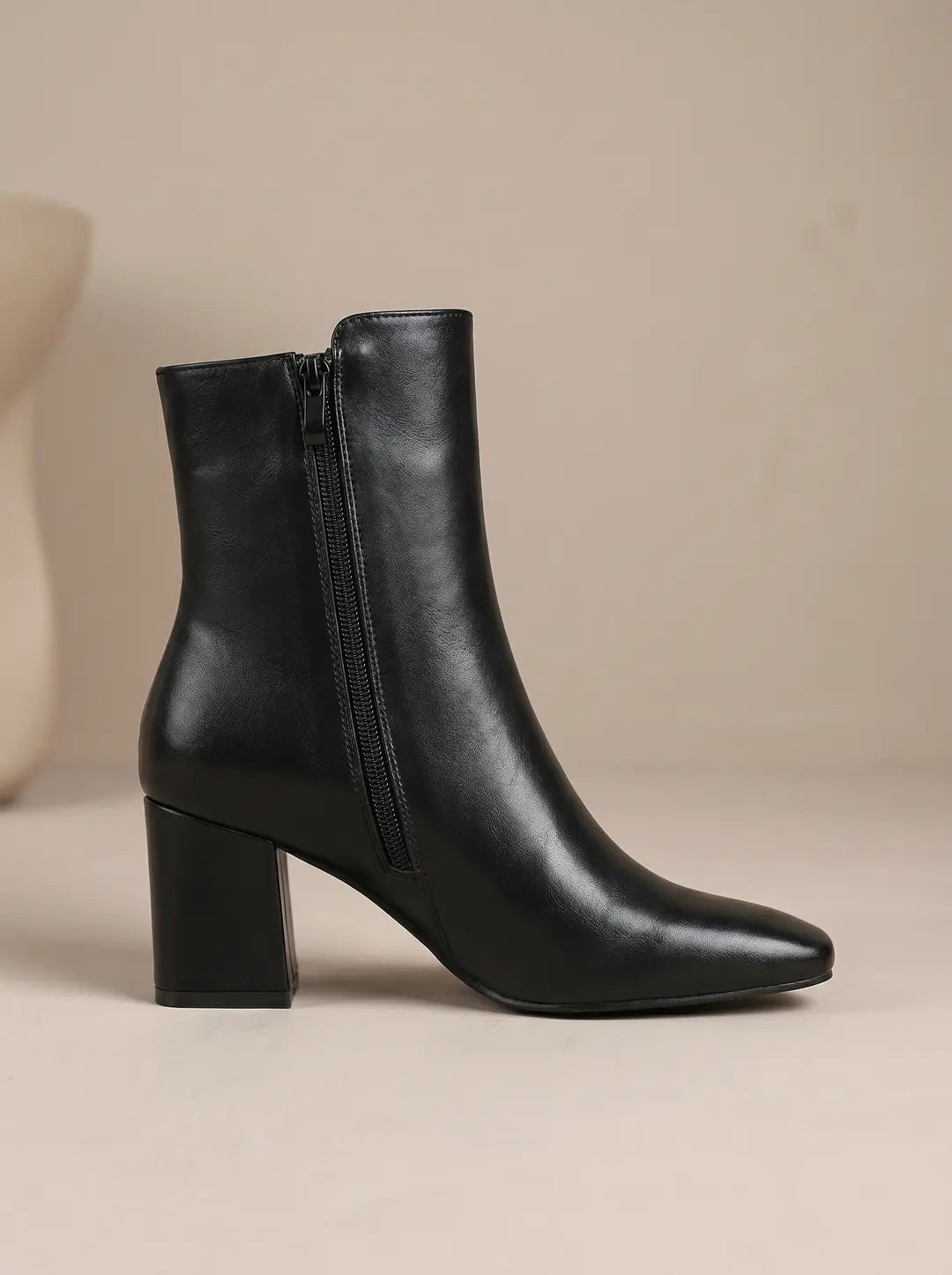 Bota de tobillo negra con tacón de bloque, punta afilada y cremallera lateral.