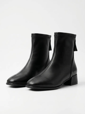 Par de botines negros de tacón bajo con cremallera trasera y una costura vertical frontal, sobre un fondo blanco.