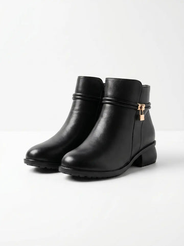 Un par de botines negros con superficie lisa. Presentan una tira decorativa alrededor del tobillo, de la cual cuelga un pequeño candado dorado y unas anillas en una de las botas. Tienen cierre de cremallera lateral y un tacón bajo con suela texturizada.